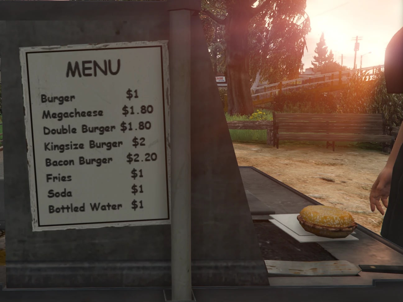 A hand-written menu board on the side of the cart listing burgers, fries, soda and water, with a burger ready on the counter